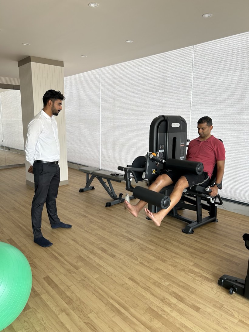 A physiotherapist supervising a patient during strength-based rehabilitation at Trivayu Physio Center