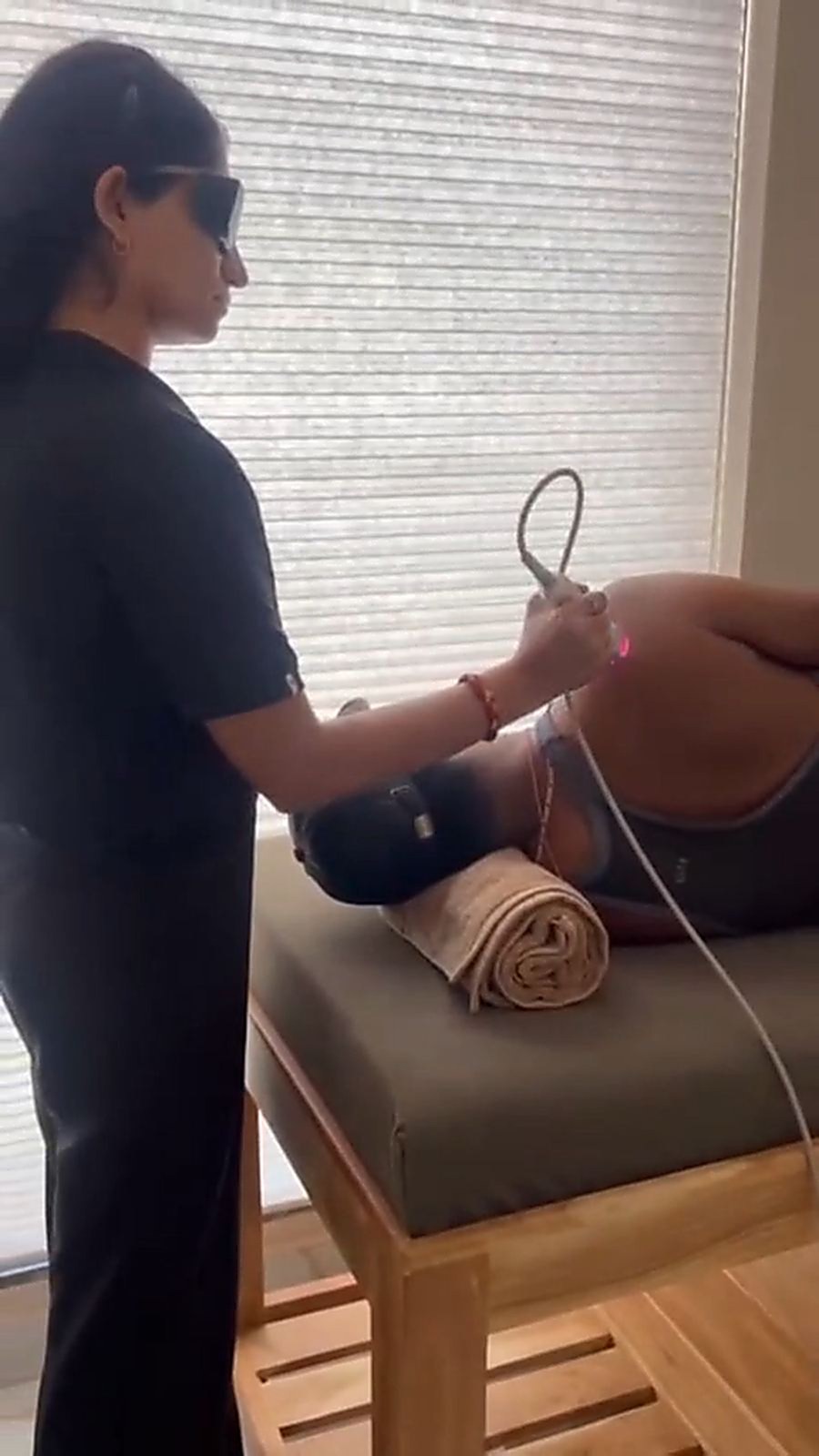 A physiotherapist at Trivayu Physio Center treating a patient's knee with laser therapy